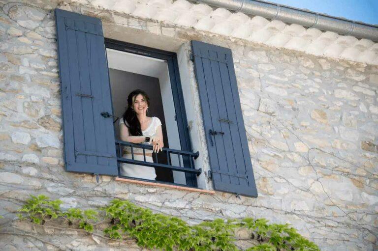 Femme portant une robe de mariée cymbeline regardant par la fenêtre d'une maison
